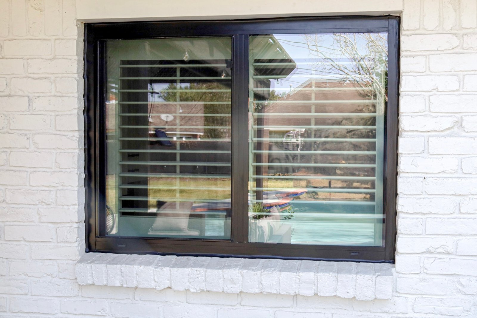 Completed black-framed window installation in a white brick wall