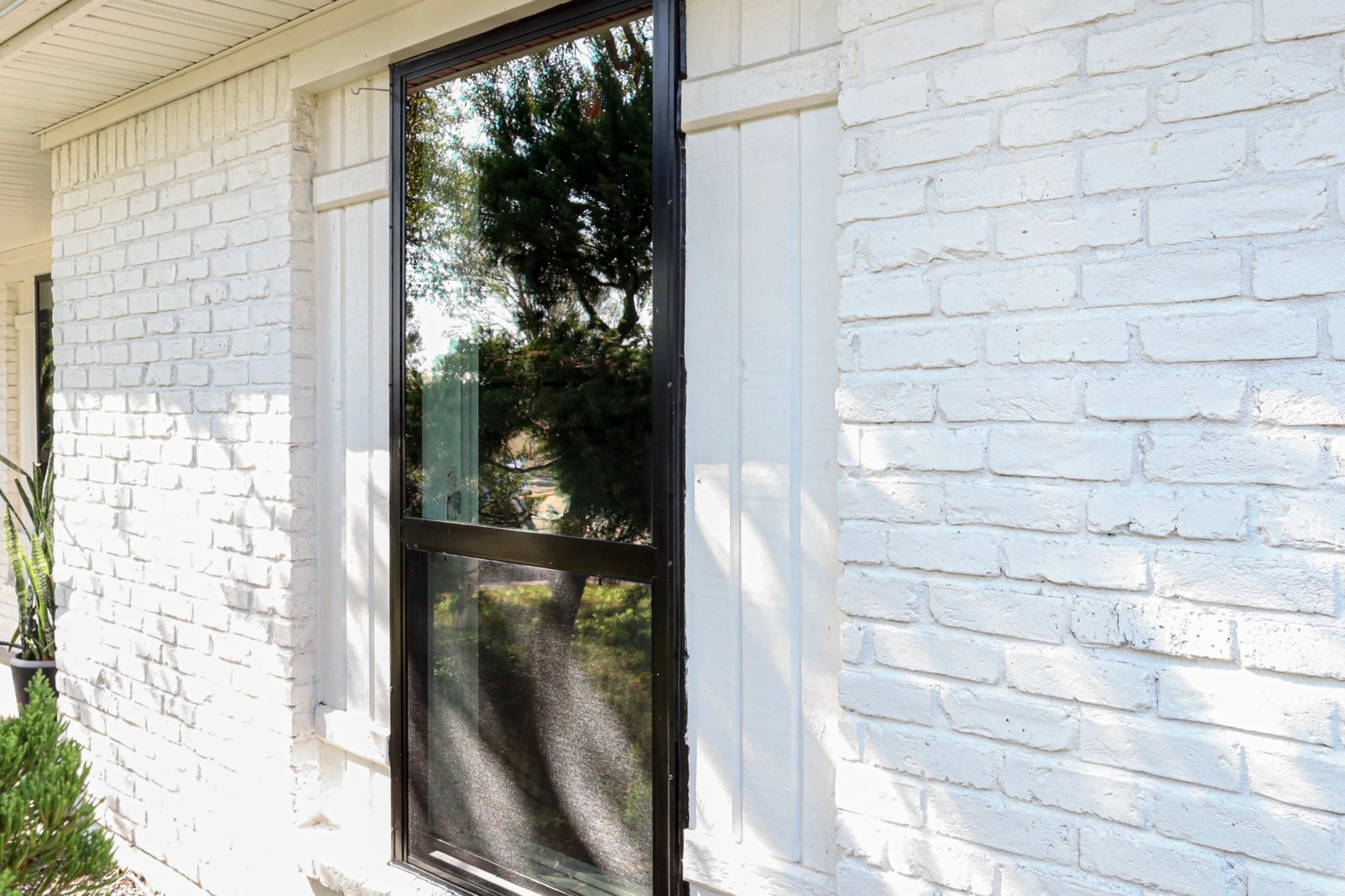 Before replacement: older dark-framed window in a white brick exterior
